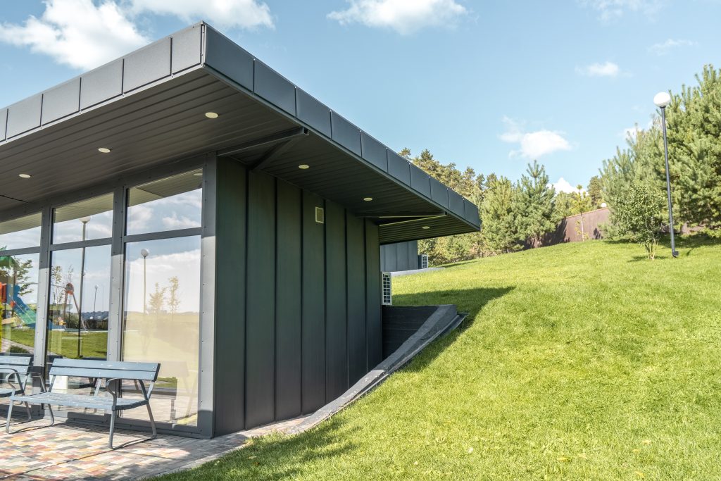 A modern garden room built on a sloped garden using raised foundations, surrounded by landscaped steps and greenery.